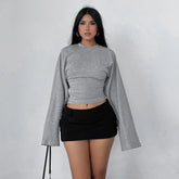 Woman wearing a gray long-sleeve crop top and black skirt